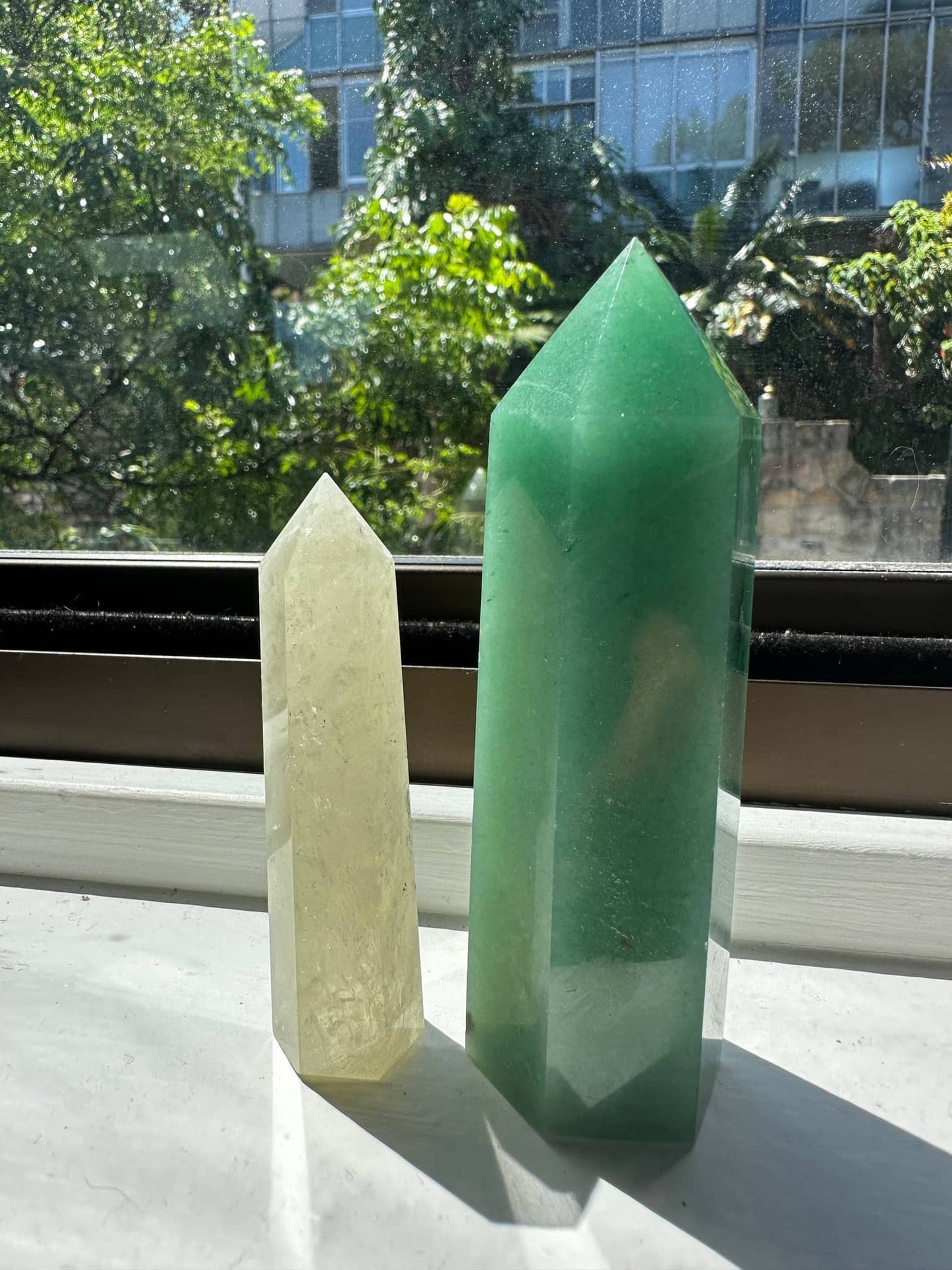 Natural Green Aventurine Tower next to a smaller crystal tower on a sunny windowsill