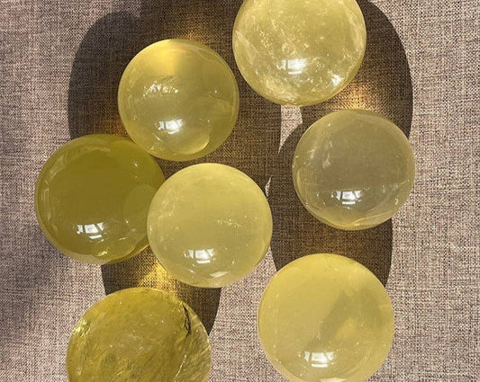 Genuine Natural Citrine Crystal Sphere set displaying various sizes and translucent colors on a textured surface